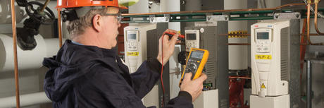 Personnel using a Fluke multimeter to control a circuit in an industrial environment